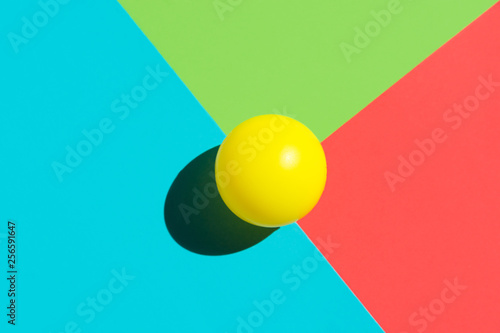Fotografie Yellow tennis ball on blue red green triangle elements