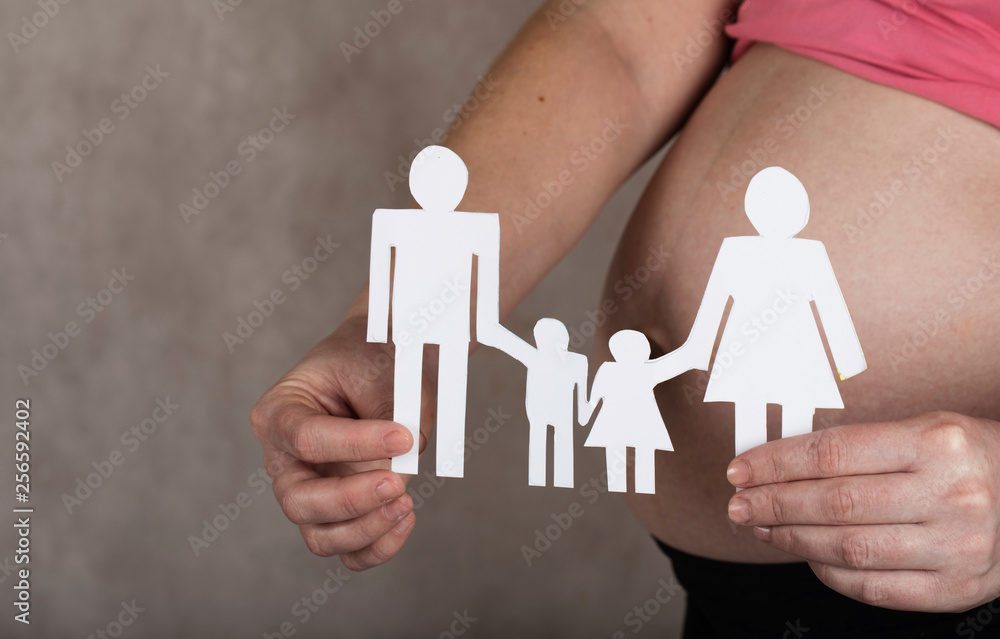 Young pregnant woman keeps paper cutouts of a family. Closeup Young pregnant woman keeps paper cutouts of a family. Closeup