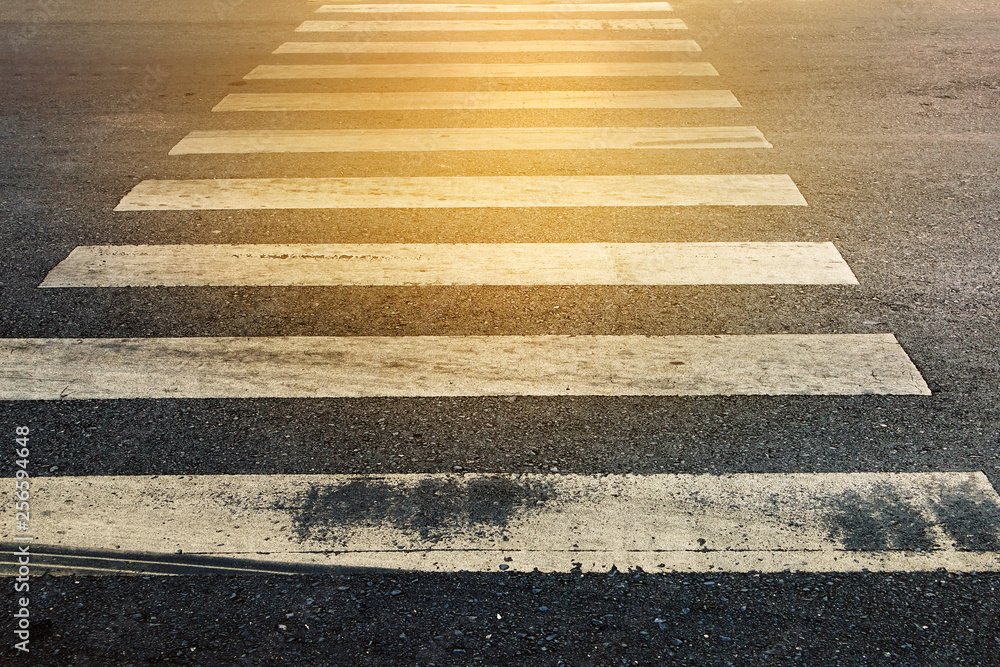 The old white-gray crosswalk on a repaired asphalt road. Concept for a safety, new beginning and step through the problem. The old white-gray crosswalk on a repaired asphalt road. Concept for a safety, new beginning and step through the problem.