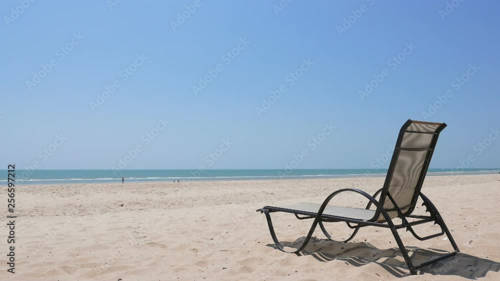 Lounge Chair on a Empty Beach with a Bright Blue Sky in the Background. Lounge Chair on a Empty Beach with a Bright Blue Sky in the Background.