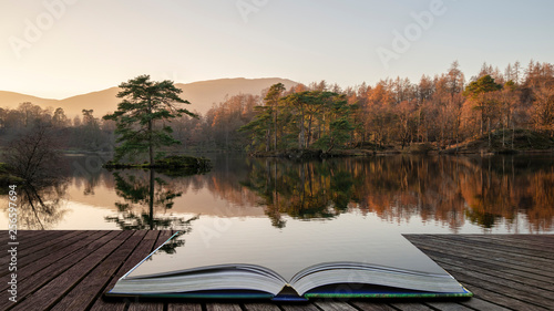 Beautiful landscape image of Tarn Hows in Lake District during beautiful Autumn Fall evening sunset with vibrant colours and still waters coming out of pages in magical story book