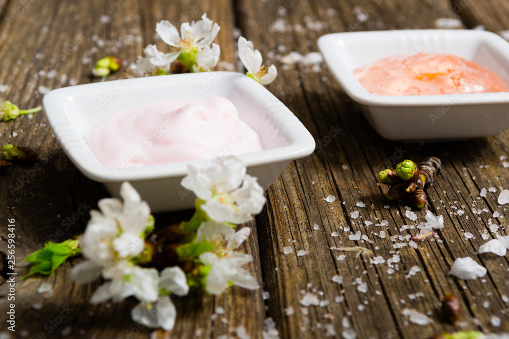 cosmetics and cherry blossom on old wooden table background