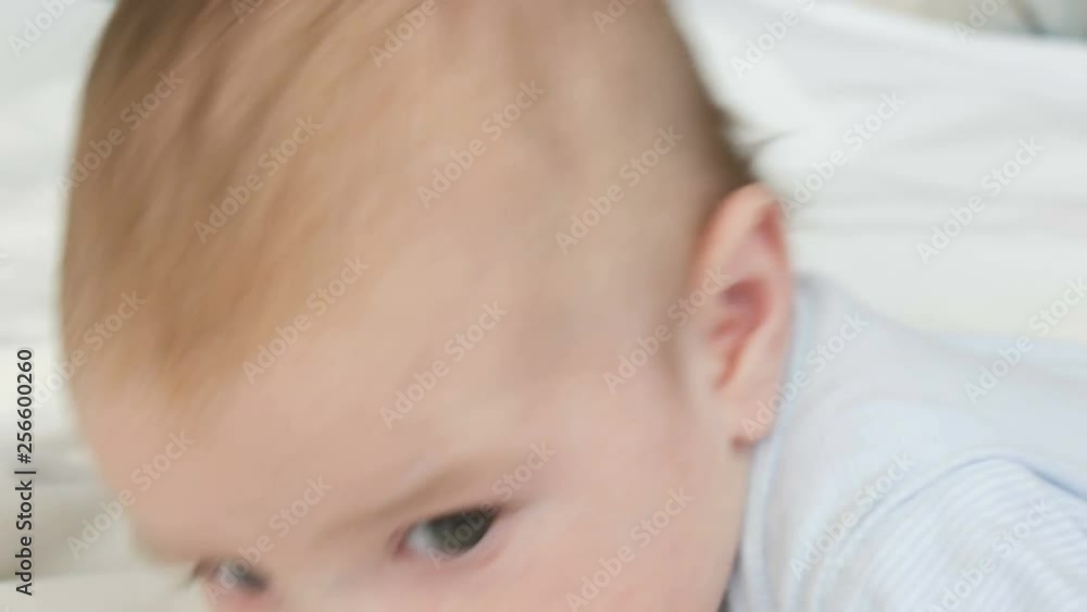 A two month old happy newborn baby lying on his stomach on the bed and experiences emotions to his mother. A baby laughs, talks, waves his arms. The child face close up view A two month old happy newborn baby lying on his stomach on the bed and experiences emotions to his mother. A baby laughs, talks, waves his arms. The child face close up view