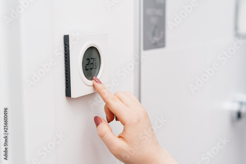 Photos Hand of a woman checking a thermostat reading