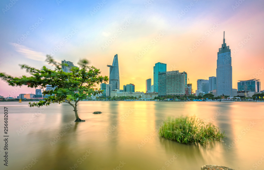 Fototapeta premium Ho Chi Minh City, Vietnam - March 4th, 2018: Riverside City sunset clouds in the sky at the end of the day brighter coal sparkling skyscrapers along the river in Ho Chi Minh City, Vietnam