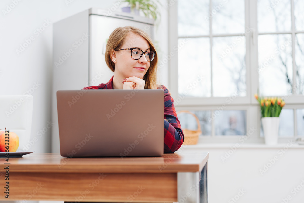 Young woman smiling while daydreaming during work Young woman smiling while daydreaming during work