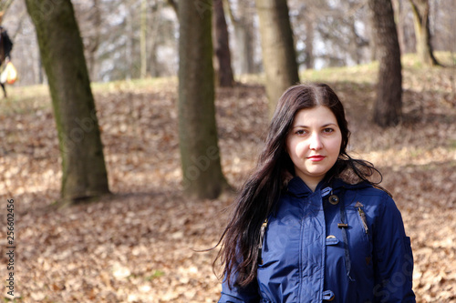 Young brunette girl with her dog walking in autumn park.