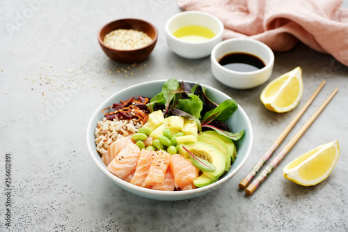 Salmon poke bowl with salad  avocado  edamame beans  pineapple and sesame Brown rice poke bowl Top view  clean eating concept Traditional Hawaiian dish