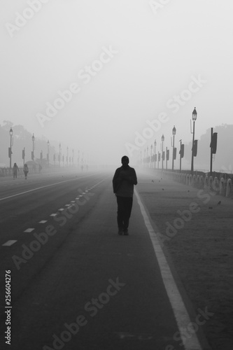man walking on the road in the fog