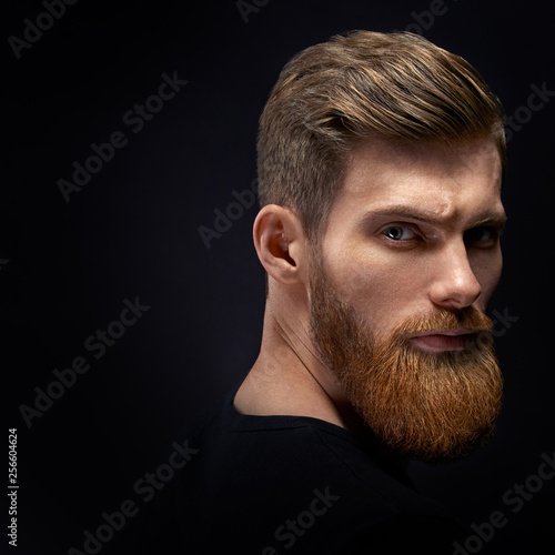 Fashion model with stylish hair and beard. Barber fashion and beauty. Portrait of handsome single bearded young man with serious expression