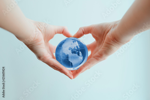 Hands in shape of heart  holding blue glass globe of South and North America