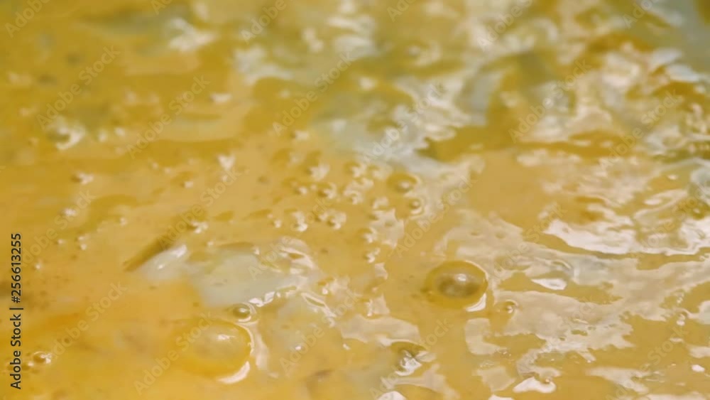 Close slow motion video of scrambling eggs in a skillet with a fork illuminated with natural lighting. Close slow motion video of scrambling eggs in a skillet with a fork illuminated with natural lighting.