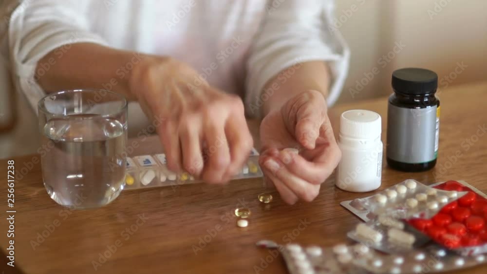 Elderly unrecognizable woman drinking a daily dose of pills with a glass of water. The hands of a person with arthritis Elderly unrecognizable woman drinking a daily dose of pills with a glass of water. The hands of a person with arthritis
