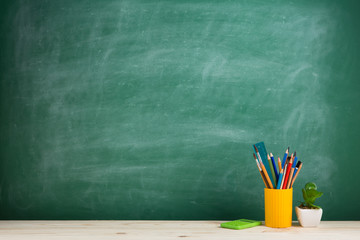 Education concept - school supplies on the desk in the auditorium, blackboard background