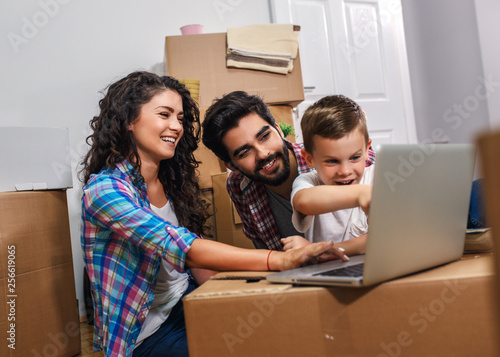 Happy young family having fun while moving into their new home. They sitting on the floor and choosing colors for the walls.