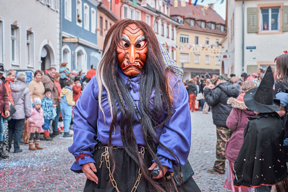 Witch in violet robe and with chain around the waist. Street Carnival in Southern Germany - Black Forest.