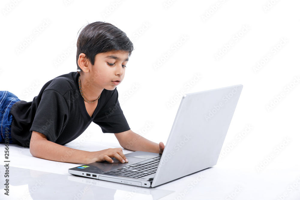 Cute little Indian/Asian boy studying or playing game with laptop computer Cute little Indian/Asian boy studying or playing game with laptop computer
