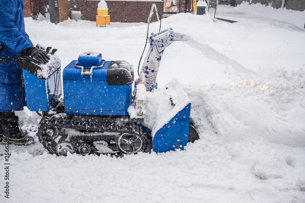 Man operating snow blower machine on the sidewalk in winter Man operating snow blower machine on the sidewalk in winter