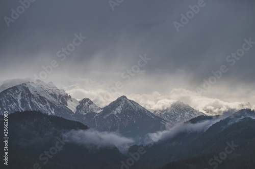 Mountains covered in snow with dark cloudy sky in rainy day