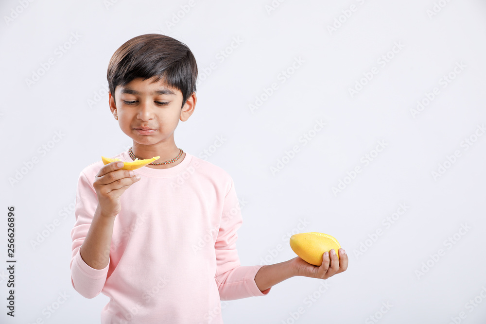 Cute indian/Asian little boy eating Mango with multiple expressions. isolated over white background Cute indian/Asian little boy eating Mango with multiple expressions. isolated over white background