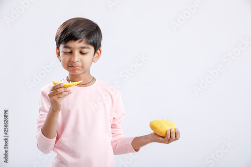 Cute indian Asian little boy eating Mango with multiple expressions. isolated over white background