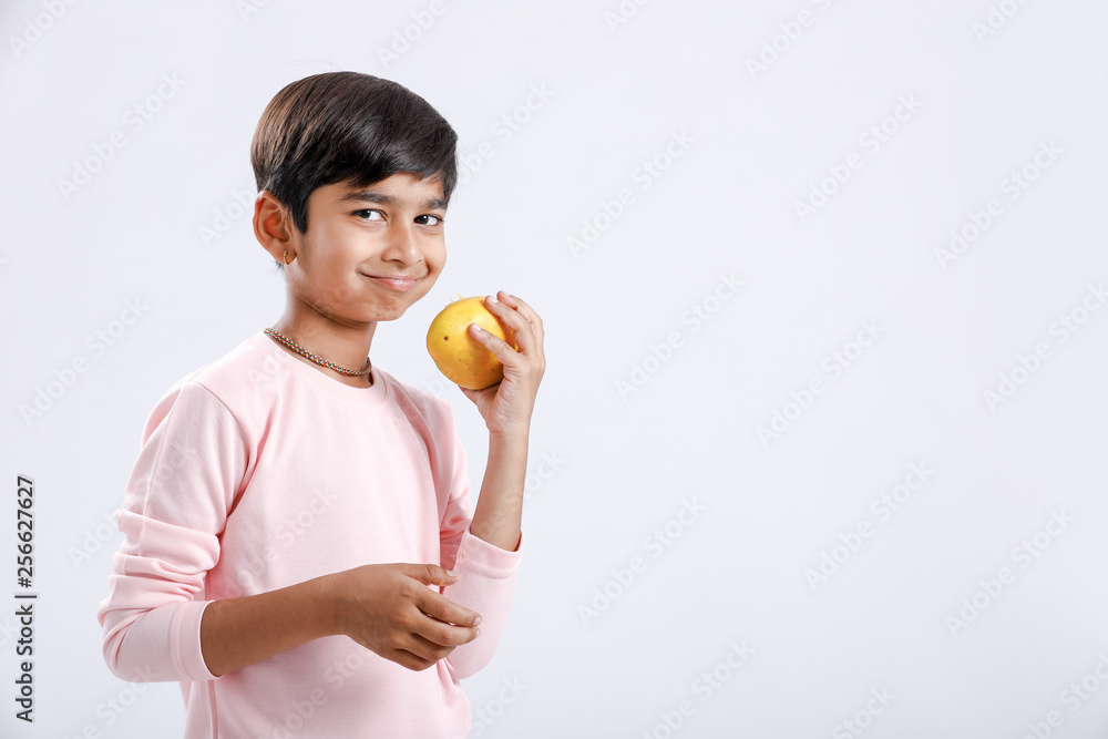 Cute indian/Asian little boy eating Mango with multiple expressions. isolated over white background Cute indian/Asian little boy eating Mango with multiple expressions. isolated over white background