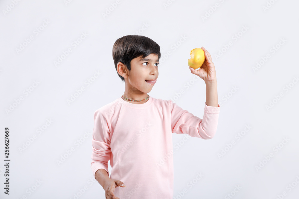 Cute indian/Asian little boy eating Mango with multiple expressions. isolated over white background Cute indian/Asian little boy eating Mango with multiple expressions. isolated over white background
