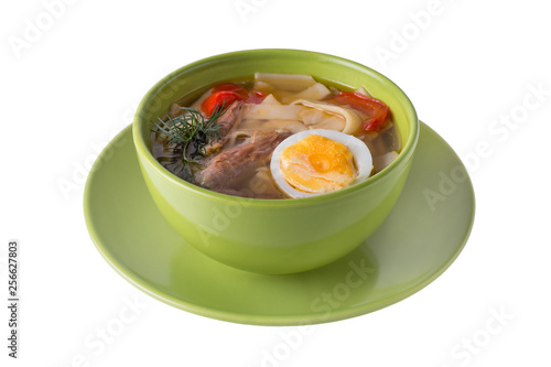 Chicken soup with noodels, meat pieces, herbs and egg in bowl on white background photo