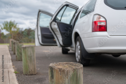 White car parked with open doors near the wooden poles