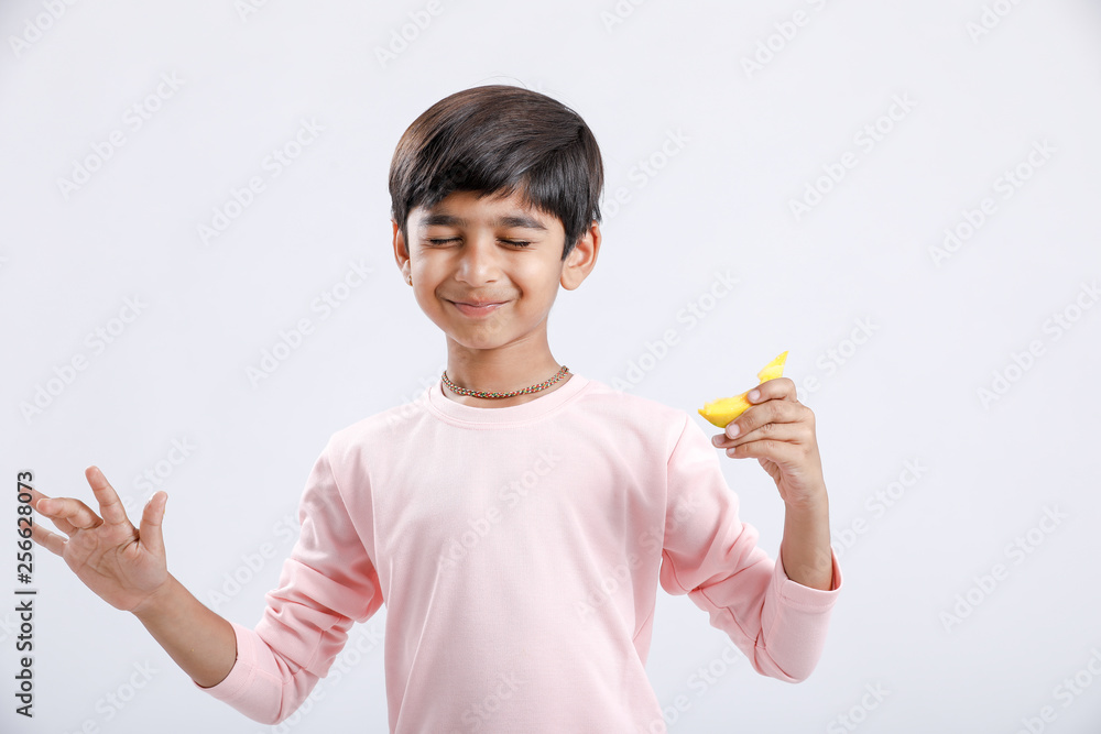 Cute indian/Asian little boy eating Mango with multiple expressions. isolated over white background Cute indian/Asian little boy eating Mango with multiple expressions. isolated over white background