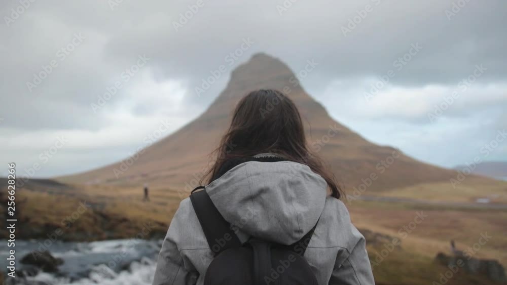 Girl stands in front of Kirkjufell, Icelandic mountain. Girl stands in front of Kirkjufell, Icelandic mountain.