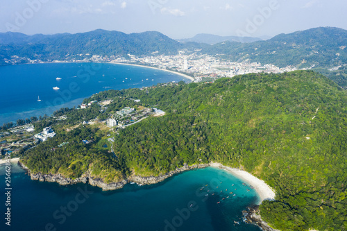 View from above, stunning aerial view of Patong city skyline in the distance and the beautiful Freedom Beach bathed by a turquoise and clear sea in the foreground, Phuket, Thailand.