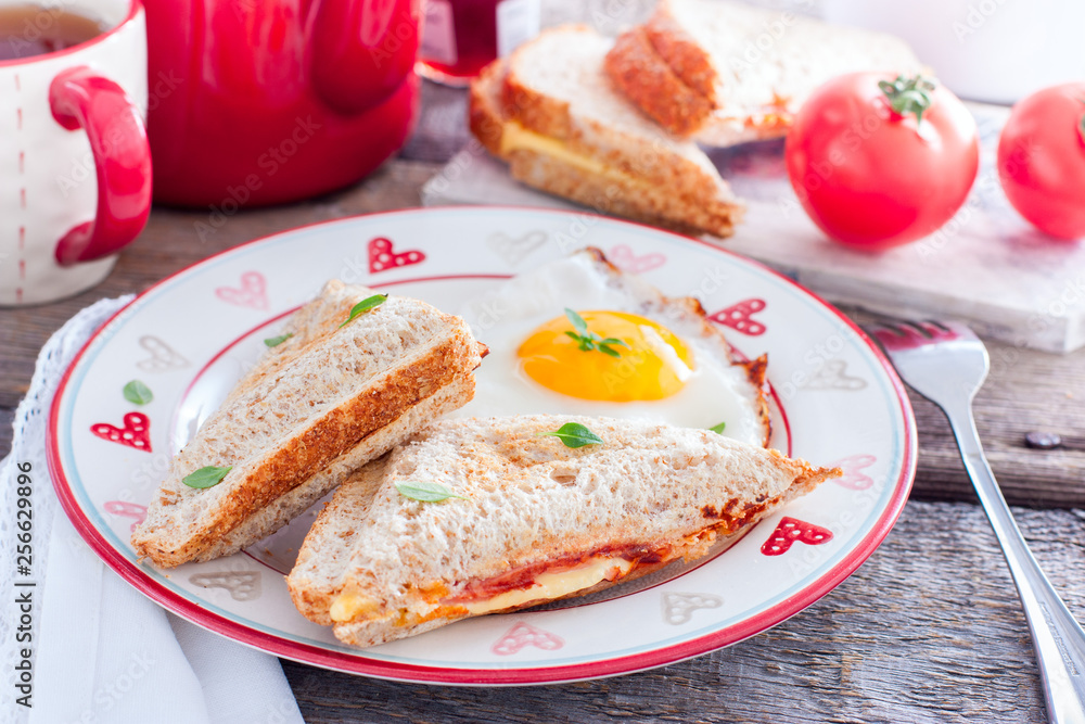 Breakfast with scrambled eggs and closed hot sandwich with cheese, tomatoes and sausage, horizontal