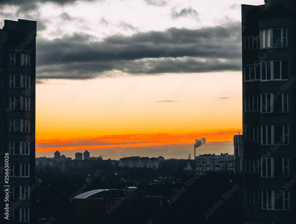 Naklejka premium dawn sunset in a European city, the rays of the sun among the houses.