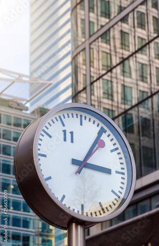 Foto Alte, analoge Uhr vor den modernen Bürogebäuden des Finanzzentrums Canary Wharf