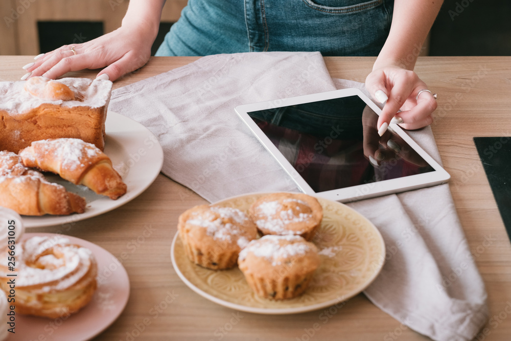 Homemade baking. Female cooking hobby. Woman browsing tablet. Fresh pastries assortment on table.