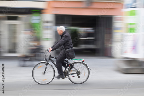 Aged man riding bicycle, motion blurred photography