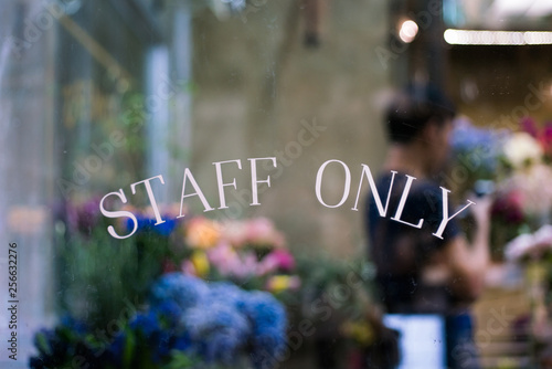 Photography Staff only sign on window with blurry background of florist working in floral sh