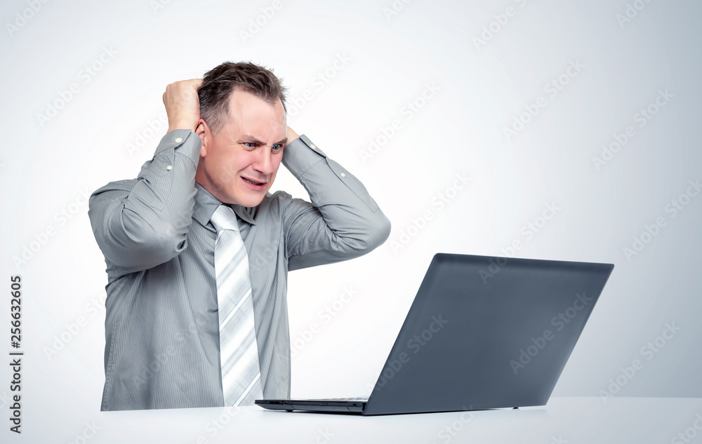 Man in horror grabs his head looking at the laptop screen. Concept of computer problems Man in horror grabs his head looking at the laptop screen. Concept of computer problems