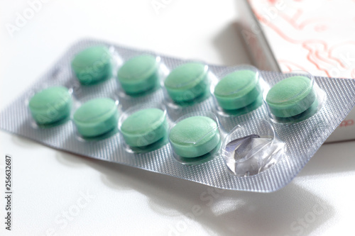 green soft gel pills in blister pack on white background.