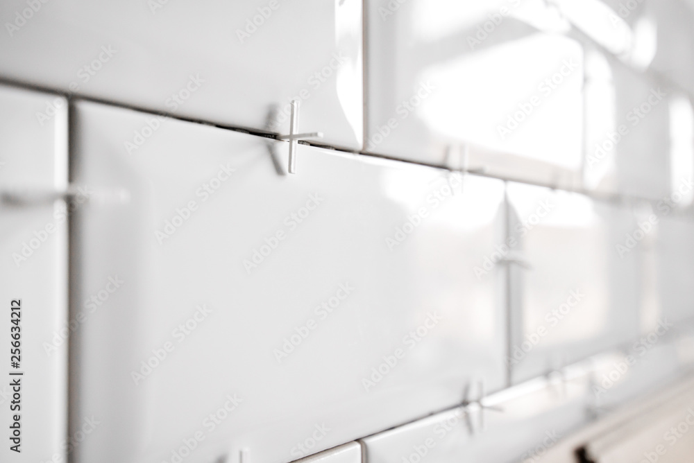 Ceramic tile lying. Installing new subway or metro tiles in bathroom, shower or kitchen back splash during home renovation. Placing or taking out tile spacers with hands and pliers. Ceramic tile lying. Installing new subway or metro tiles in bathroom, shower or kitchen back splash during home renovation. Placing or taking out tile spacers with hands and pliers.