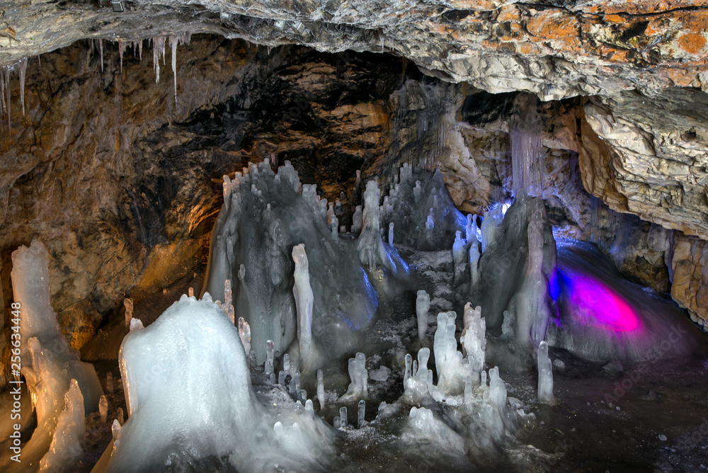 Underground glacier in Glaciers Cave in Apuseni mountains, Scarisoara,  Romania. Ice and big icicles with colorful back light. Stalactites and  stalagmites in dark cave Photos | Adobe Stock