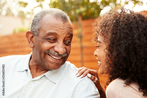 Senior black man and his adult granddaughter laughing outdoors, close up photo