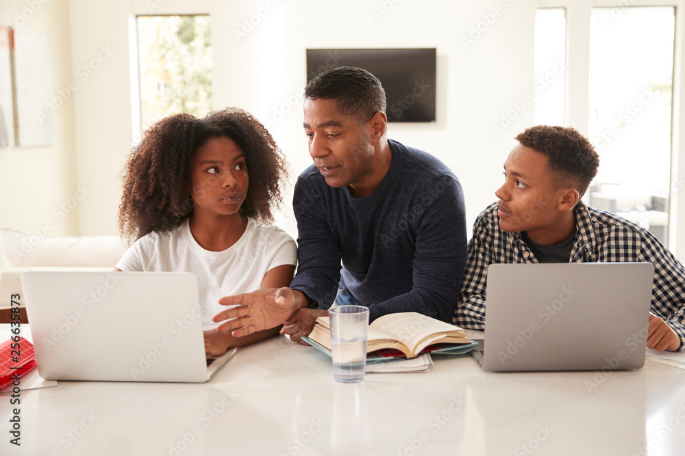 Middle aged black dad helping his teen kids with their homework, front view, close up Middle aged black dad helping his teen kids with their homework, front view, close up