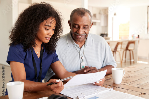 Female healthcare worker checking test results with a senior man during a home health visit photo