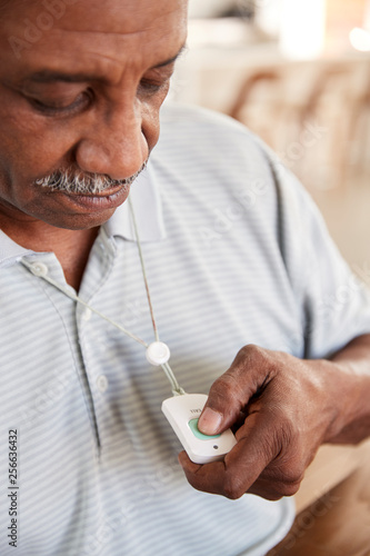 Senior black man pushing an assistance alarm which heâ€™s wearing around his neck, close up, vertical photo