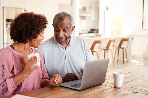 Senior black man and his middle aged daughter using a laptop together at home, close up