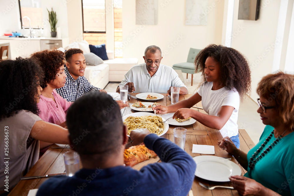 © Monkey Business - Three generation black family sitting at dinner table eating together, elevated view