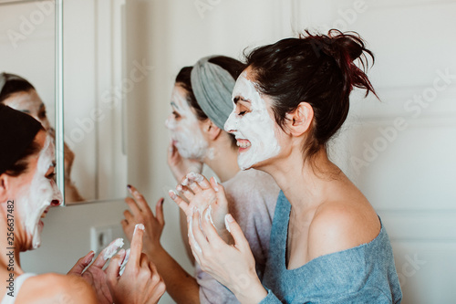 .Group of friends applying a revitalizing white mask on their faces. Beauty treatment  skin care  natural  spa and fun moments. Lifestyle.