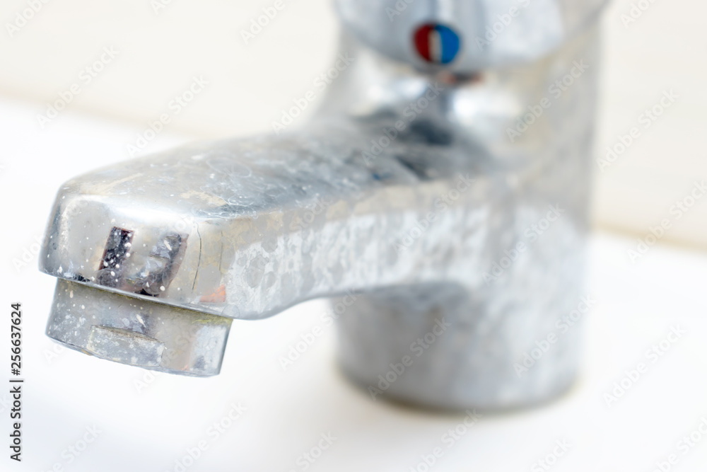 Dirty faucet with limescale, calcified water tap with lime scale on washbowl in bathroom Stock
